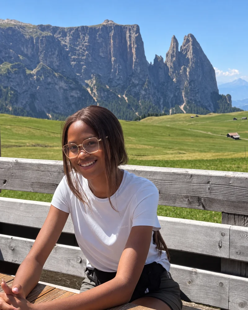 Brenda Nyaboke smiling outdoors with mountains and green hills behind her